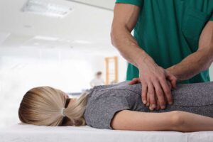 Clinician assessing a seated adult with shoulder and back pain using gentle movement tests.
