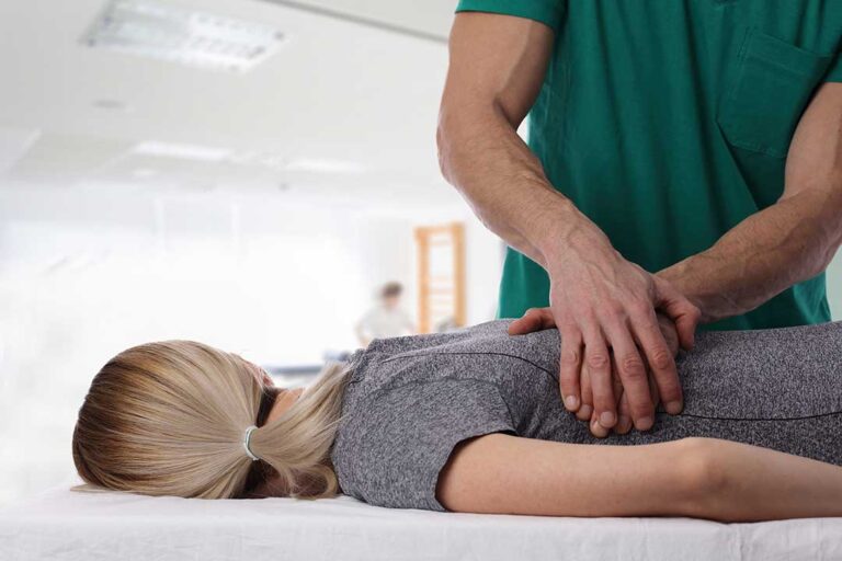 Clinician assessing a seated adult with shoulder and back pain using gentle movement tests.